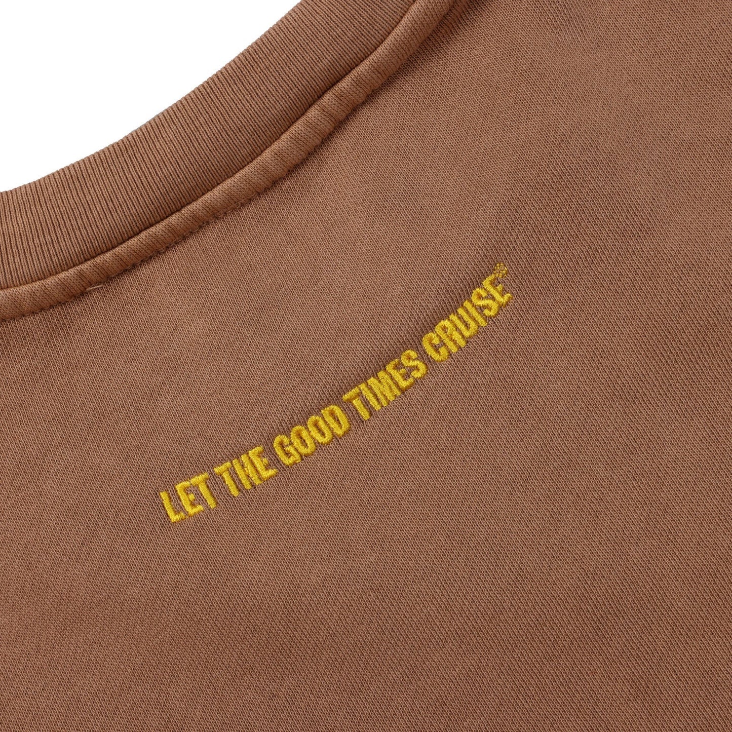 A close-up of the upper back of a light brown crewneck sweatshirt. The phrase 'LET THE GOOD TIMES CRUISE' is embroidered in yellow text, running diagonally across the fabric.