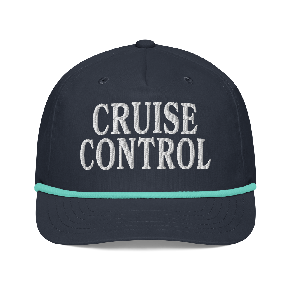 A dark navy blue baseball cap with 'CRUISE CONTROL' embroidered in white on the front, accented by a thin mint green stripe on the brim.