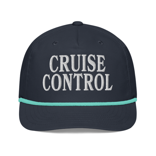 A dark navy blue baseball cap with 'CRUISE CONTROL' embroidered in white on the front, accented by a thin mint green stripe on the brim.