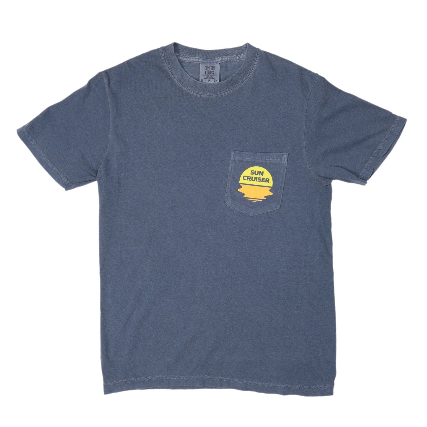 A flat lay of a faded blue short-sleeved t-shirt with a pocket on the left chest. A yellow and orange sun-shaped logo is printed on the pocket, featuring the words 'SUN CRUISER' in blue text. The logo evokes a sunset over water.
