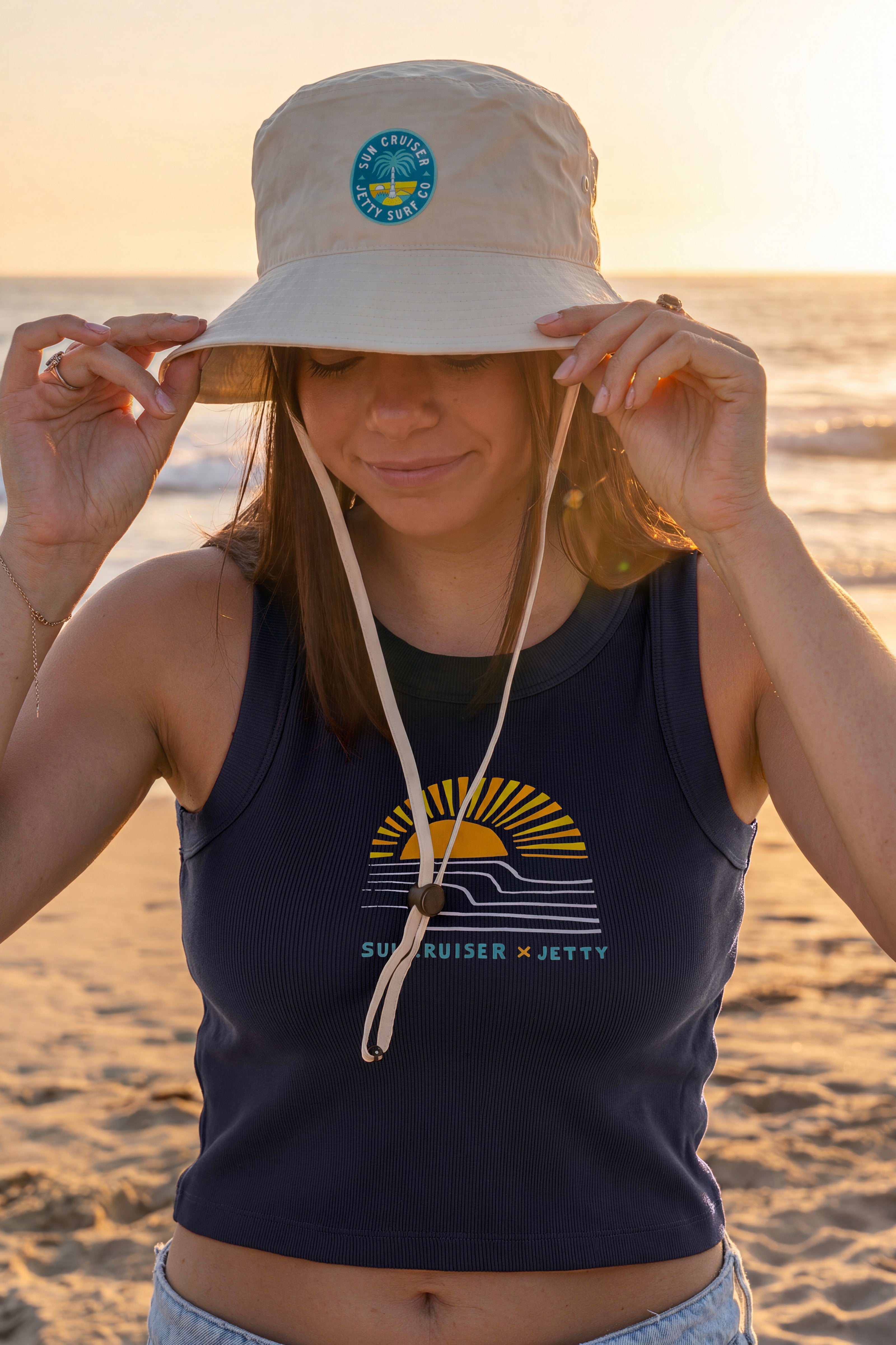 Person wearing a navy tank top with a logo on a beach