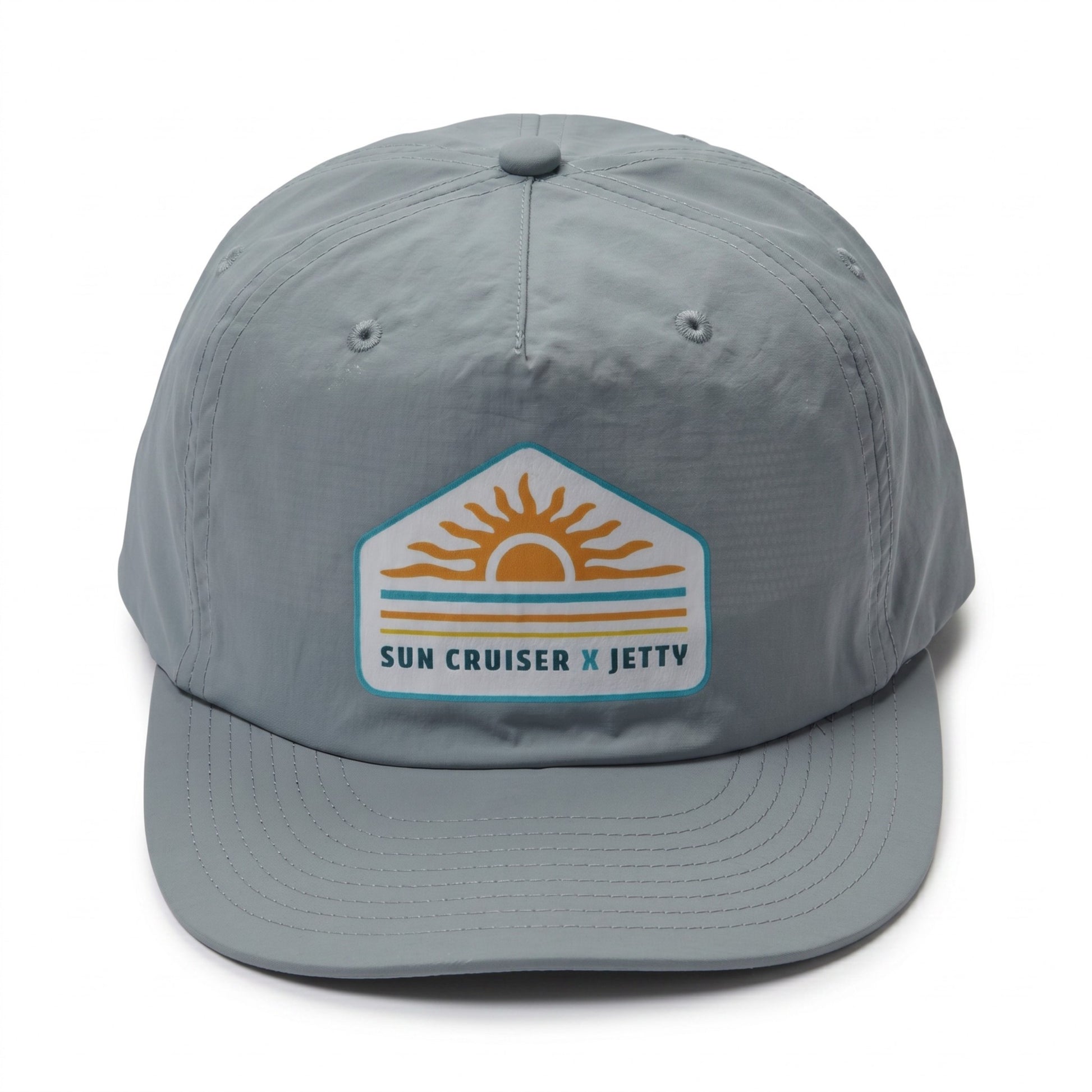 A light gray 5-panel baseball cap featuring a 'Sun Cruiser x Jetty' patch on the front, set against a plain white background.