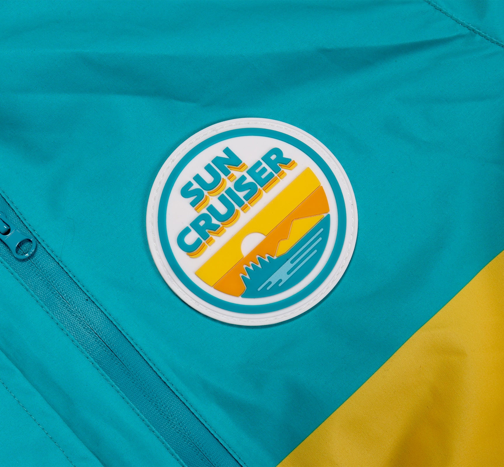 Close-up of a 'Sun Cruiser' logo on a teal and yellow ski suit