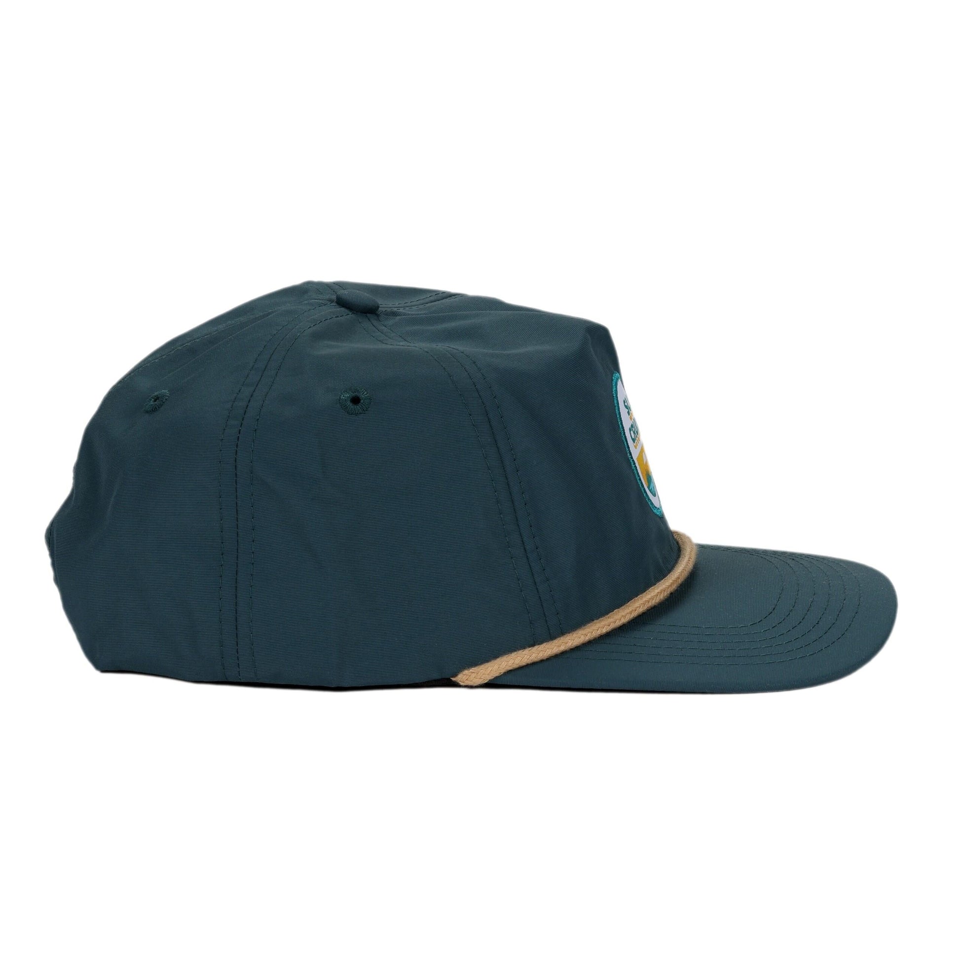 A side view of a navy blue hat with a flat brim and a tan rope accent at the base of the crown. A small portion of a circular blue and white logo is visible on the front of the hat.