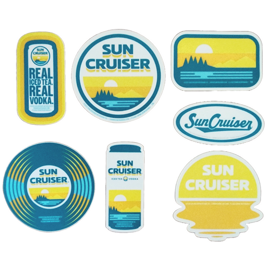 A collection of seven Sun Cruiser themed stickers of various shapes and colors is displayed. These include rectangular stickers with text like "SUN CRUISER" and "REAL ICED TEA. REAL VODKA.", and others featuring sunset and mountain graphics. There's also an oval sticker with "Sun Cruiser" in script, and a can-shaped sticker.