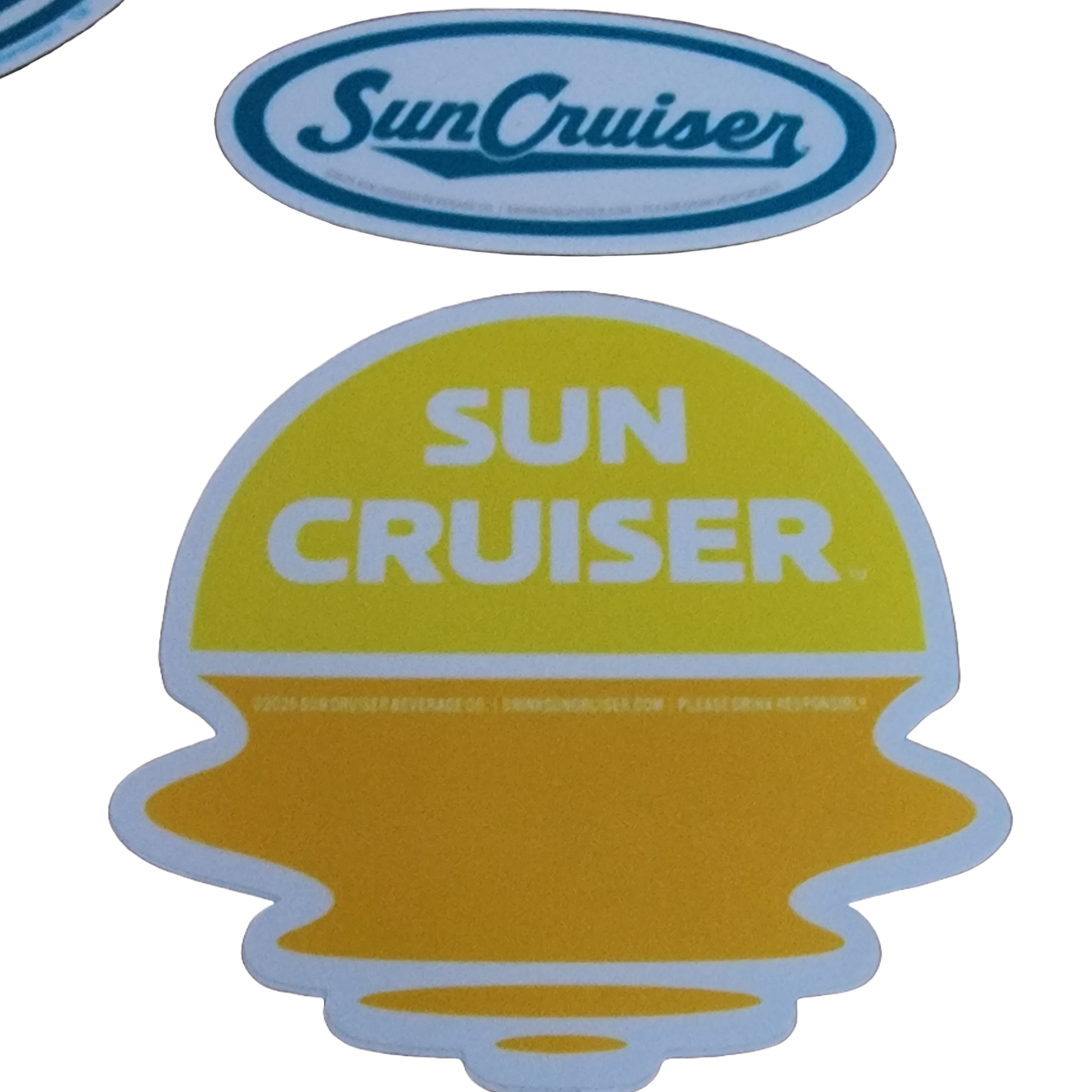 A collection of Sun Cruiser themed stickers of various shapes and colors is displayed on a light grey background, featuring branding and graphics like sunsets over landscapes.